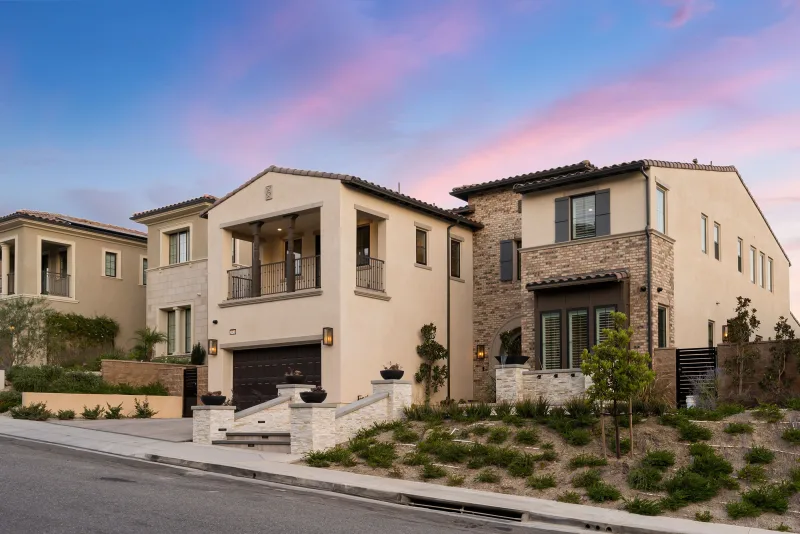 Two-storey stucco homes on a desert street under a pink dawn sky