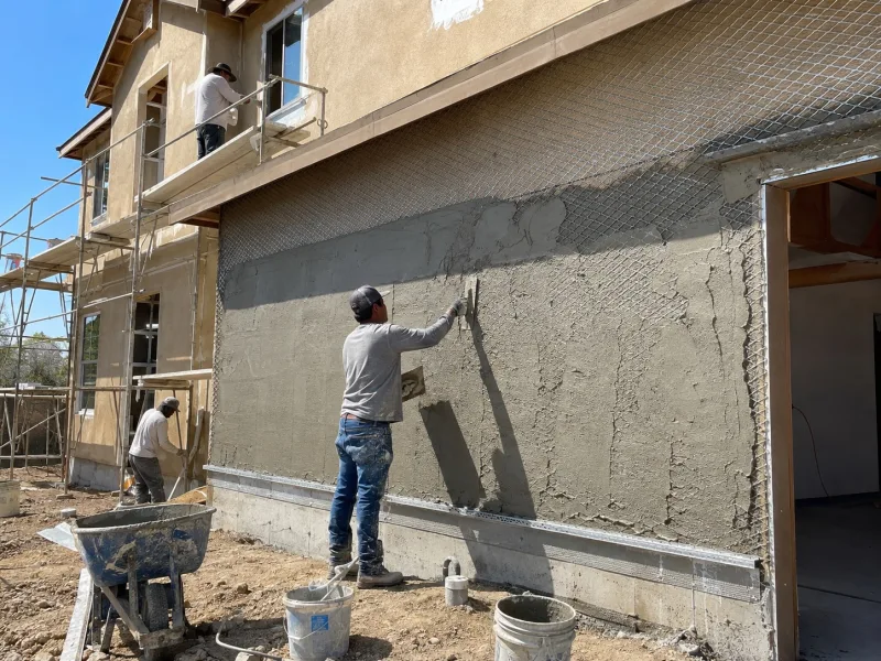 Brown coat going on over metal lath on a new stucco wall